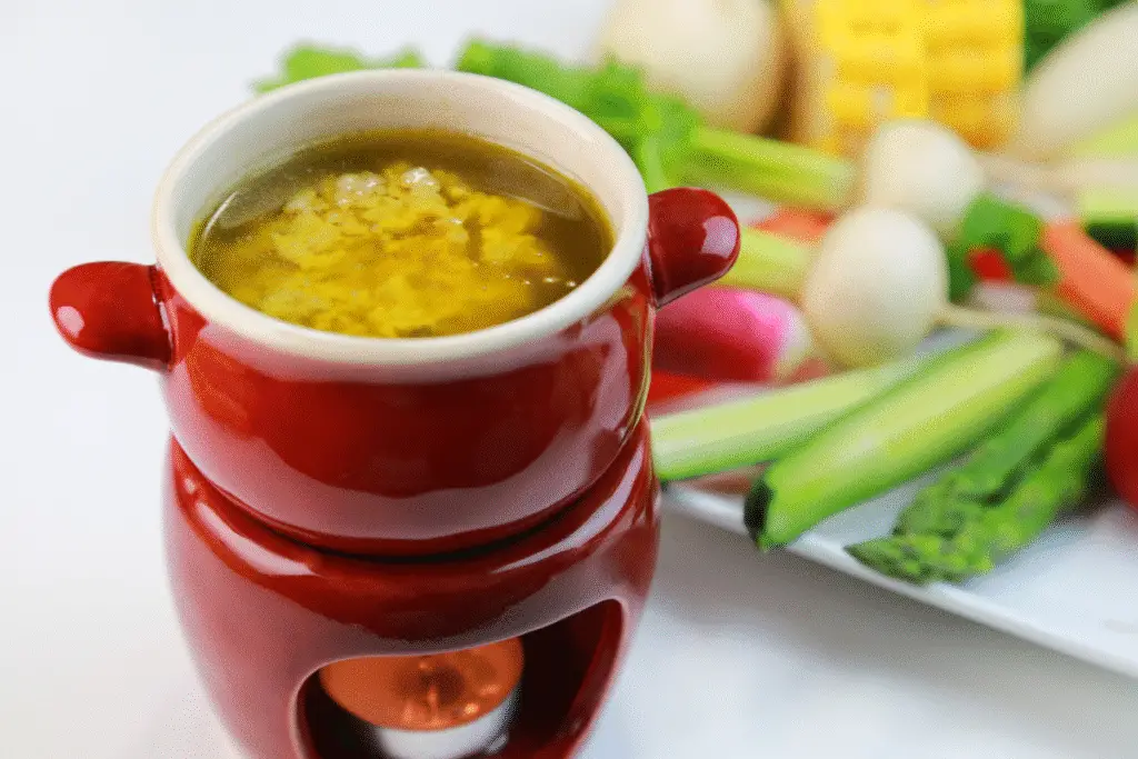 Bagna cauda recipe served in a ceramic bowl, surrounded by colorful fresh vegetables ready for dipping at a rustic Italian-style table.