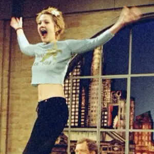 Drew Barrymore in 90s grunge-inspired outfit with messy hair and vintage casual style