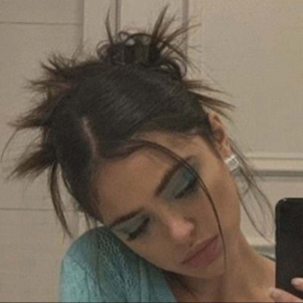 Woman with grunge makeup and hair styled in two messy buns for an edgy alternative look.
