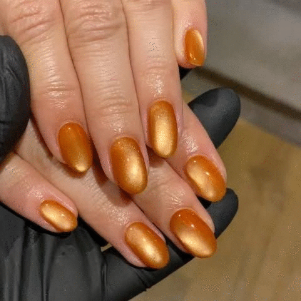 Short orange cat eye nails with a sleek glossy finish and bold magnetic shine.