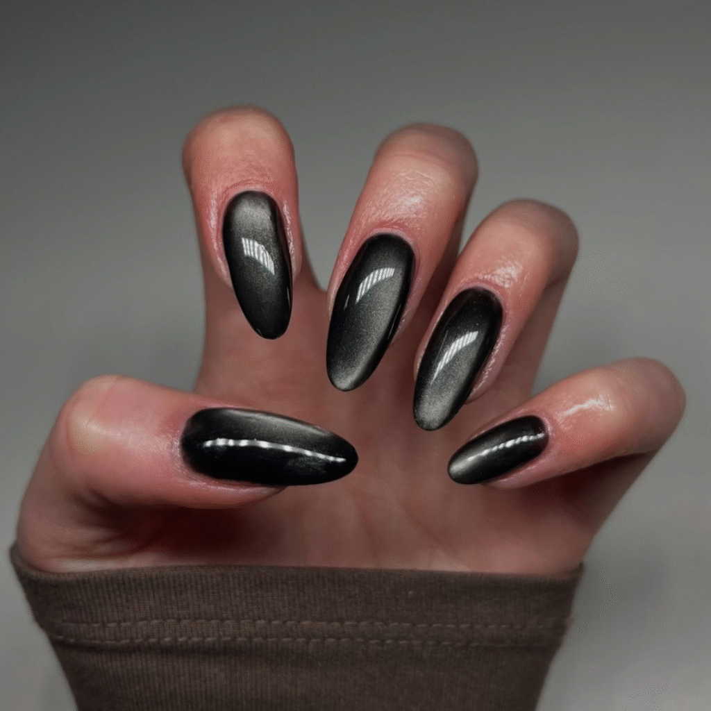 Long black cat eye nails with round tips and dramatic magnetic reflection.