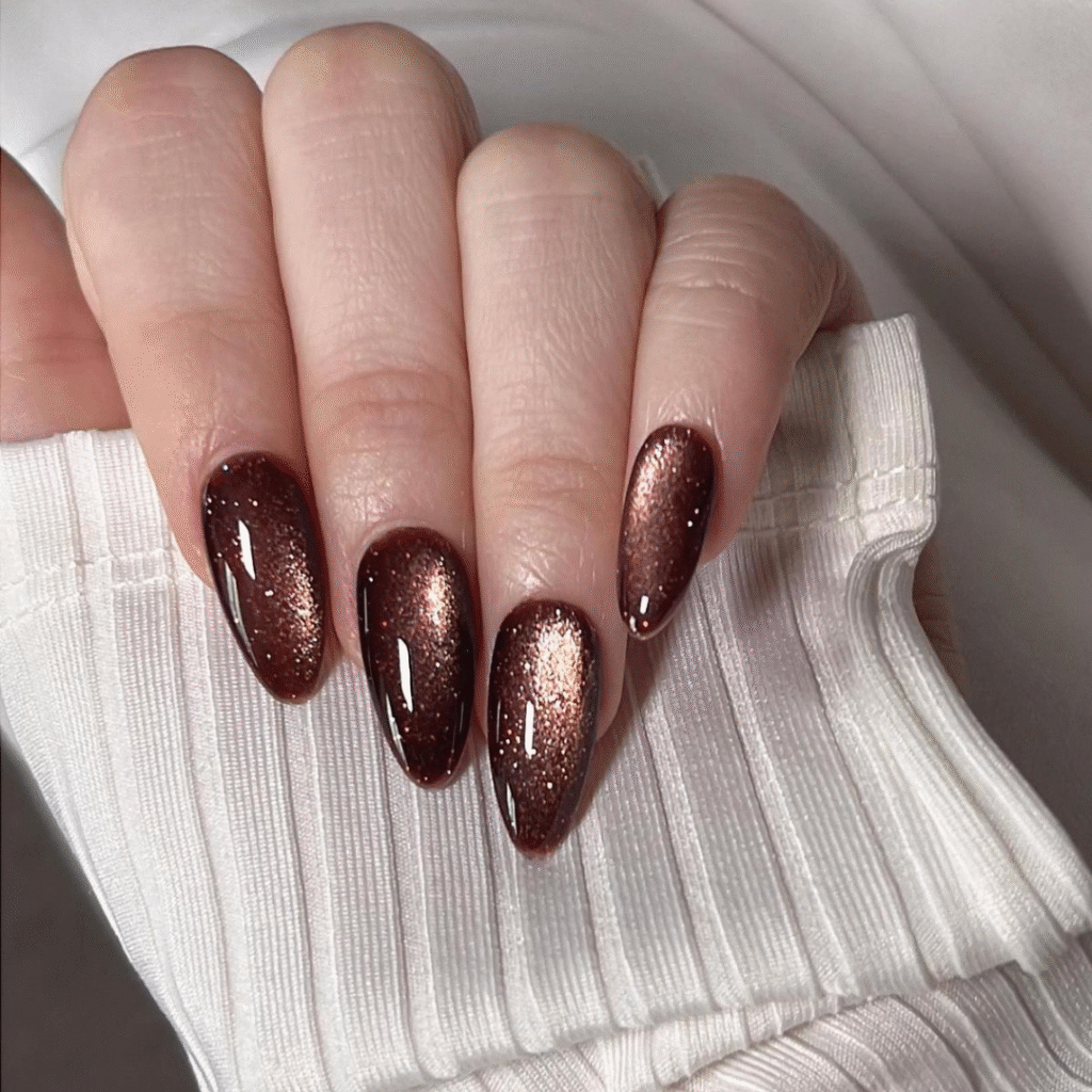 Long brown cat eye nails with deep caramel shimmer and rich metallic tone.