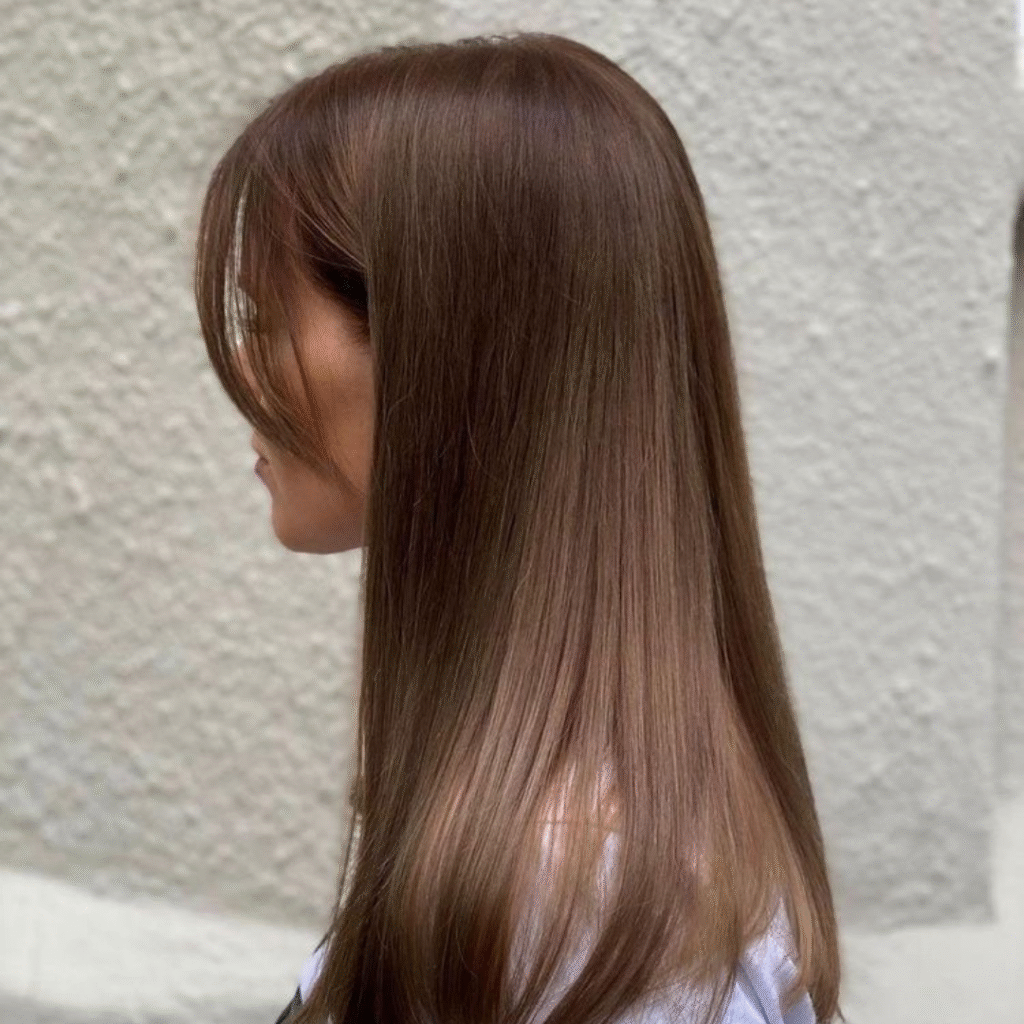 Blonde woman with long hair showing how to style curtain bangs from the side, with soft volume and smooth layers.